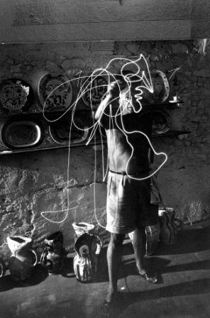 Artist Pablo Picasso standing in front of ceramic plates and pitchers he has created as he uses flashlight to make light drawing of what appears to be a woman in the air.  (Photo by Gjon Mili//Time Life Pictures/Getty Images)